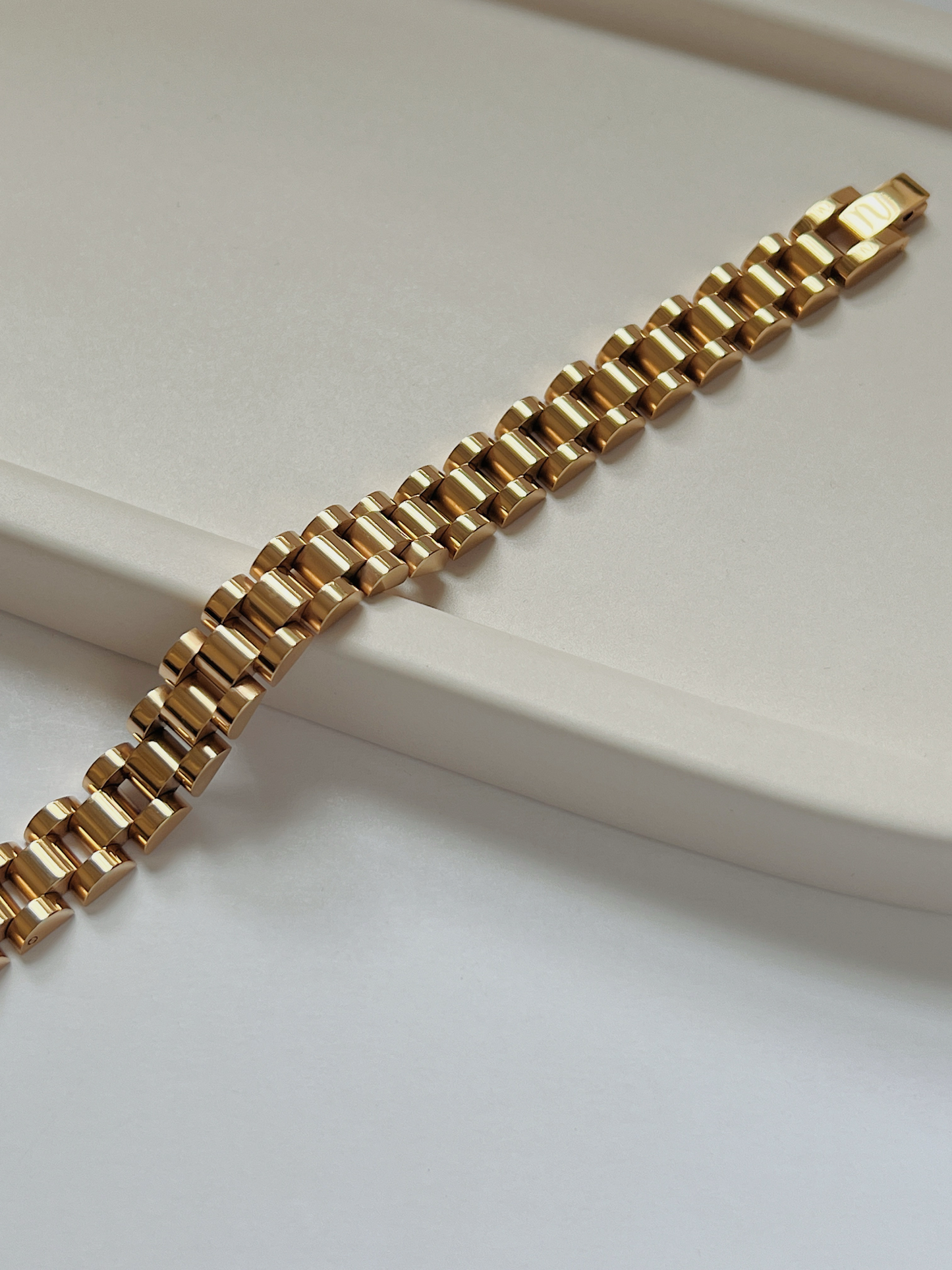 Close-up detail of the secure flush-folding clasp on the 18K gold PVD watch link bracelet.