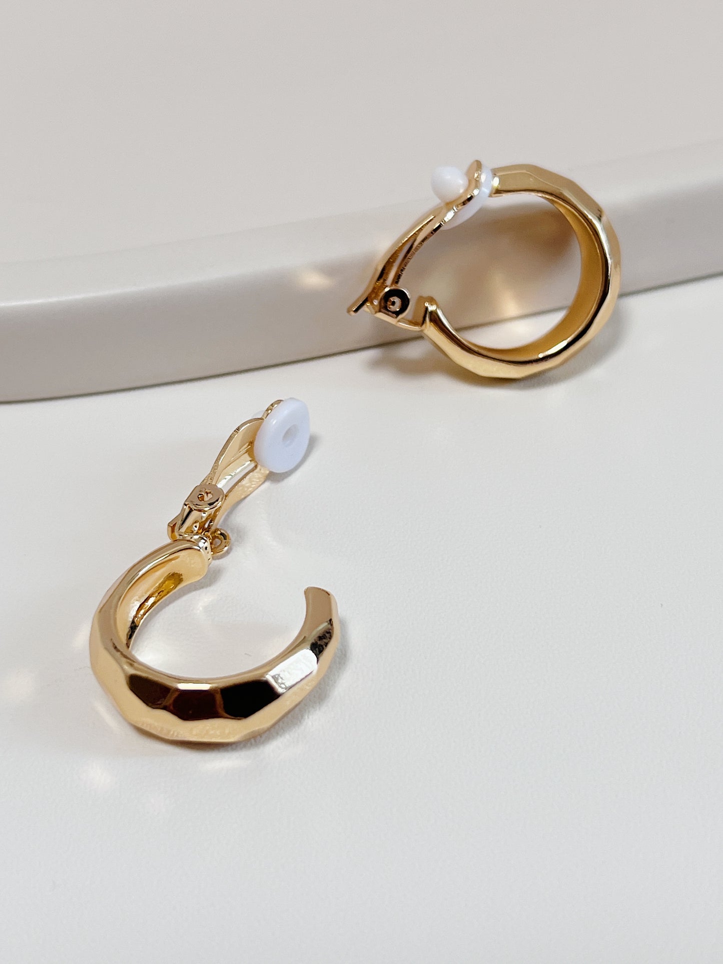 Gold hoop earrings on a light gray background