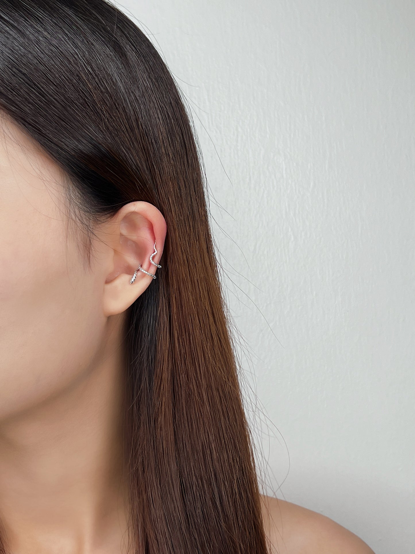model styling aurous atelier hypoallergenic victoria s925 serpent ear cuff earrings on left ears.