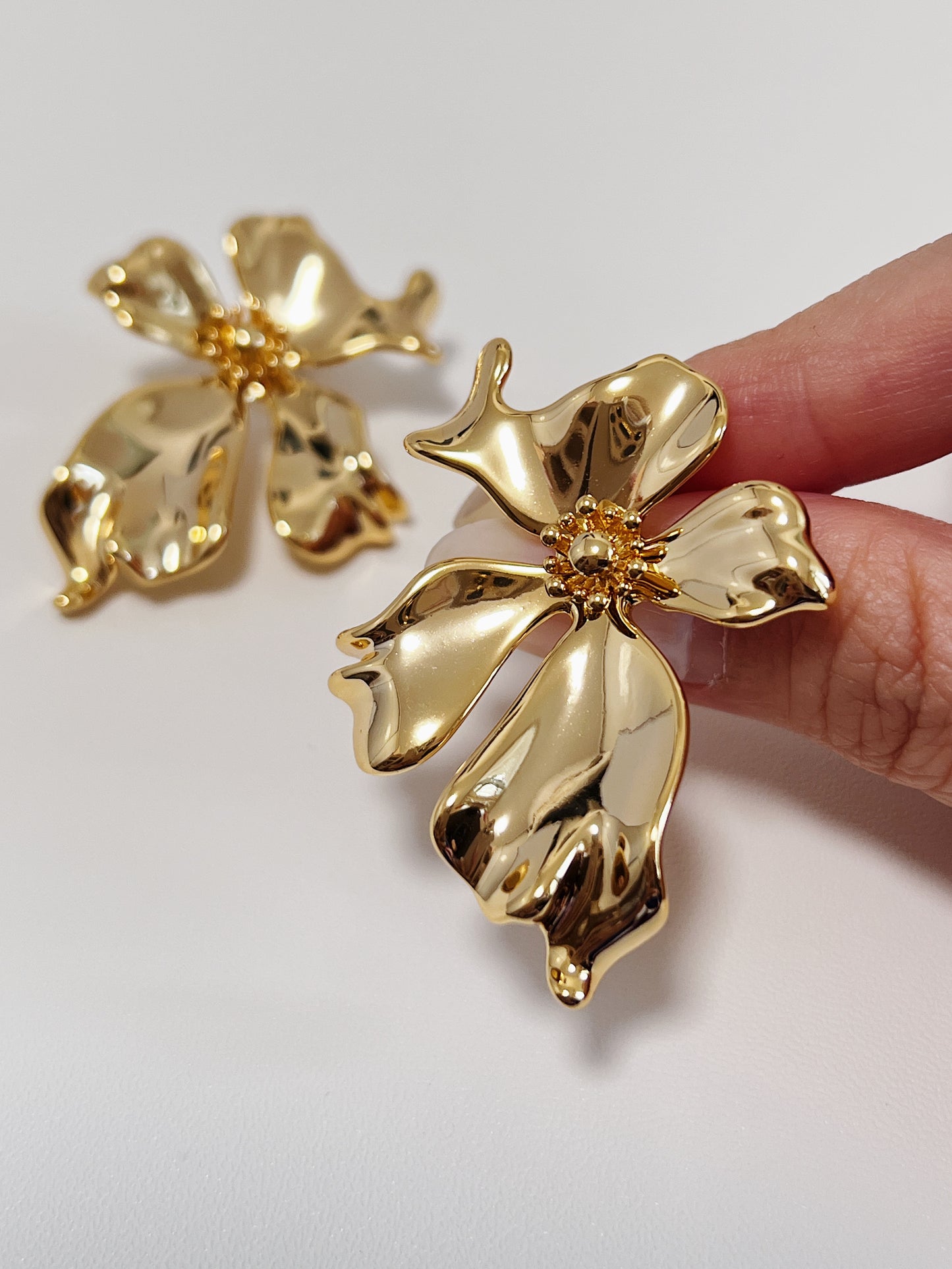 Gold floral earrings on a light gray background