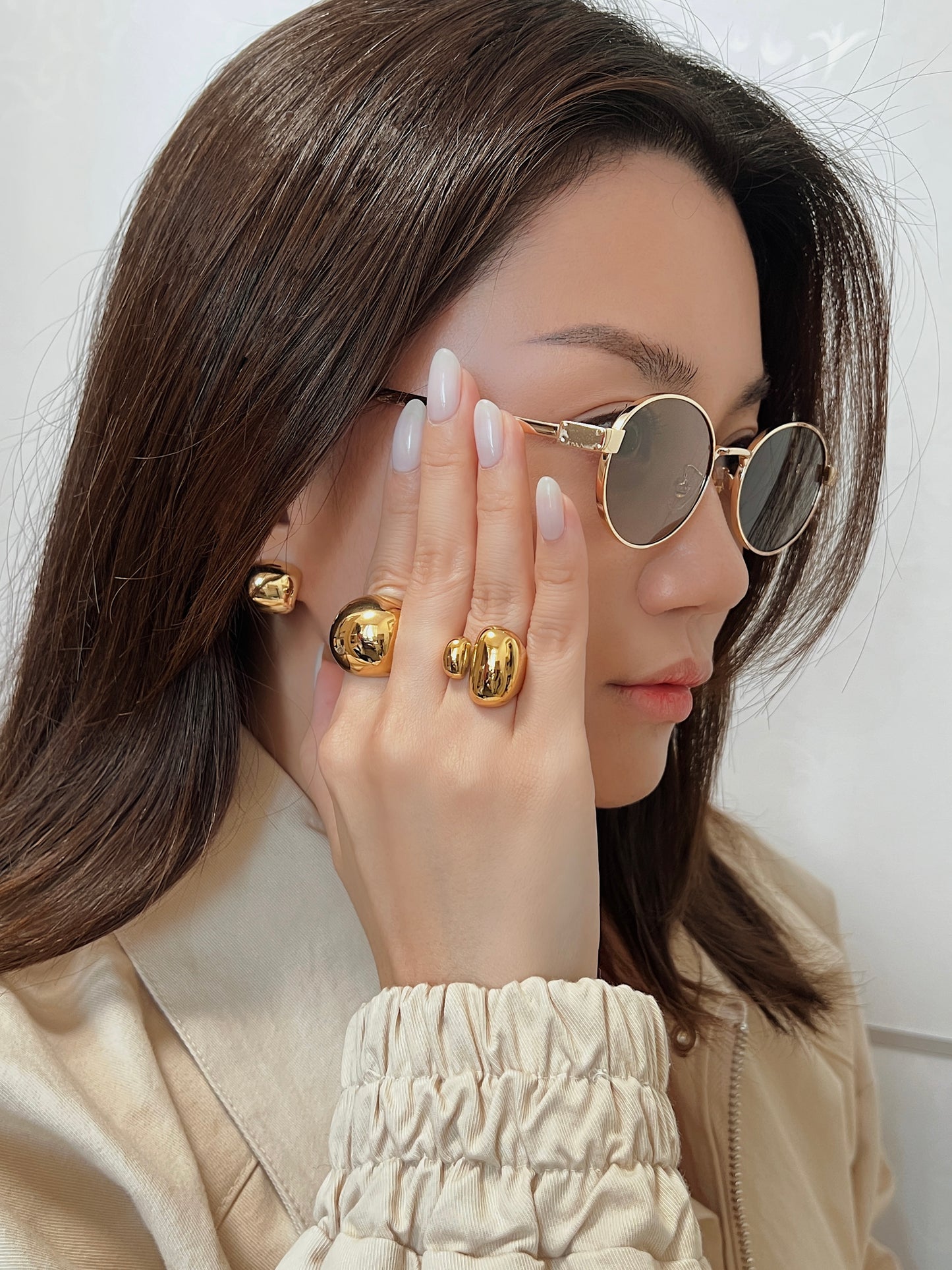 Close-up of model wearing thick gold statement band with a modern bomber jacket