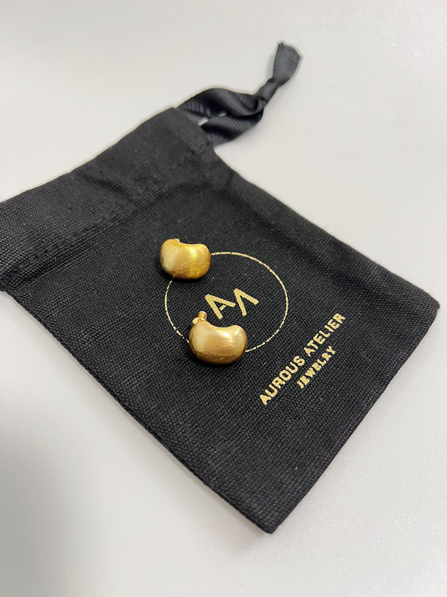 brushed design stud earrings, matte-finished earrings, classic stud earrings, contemporary earrings, brushed curve studs on a jewelry packaging, aurous atelier packaging