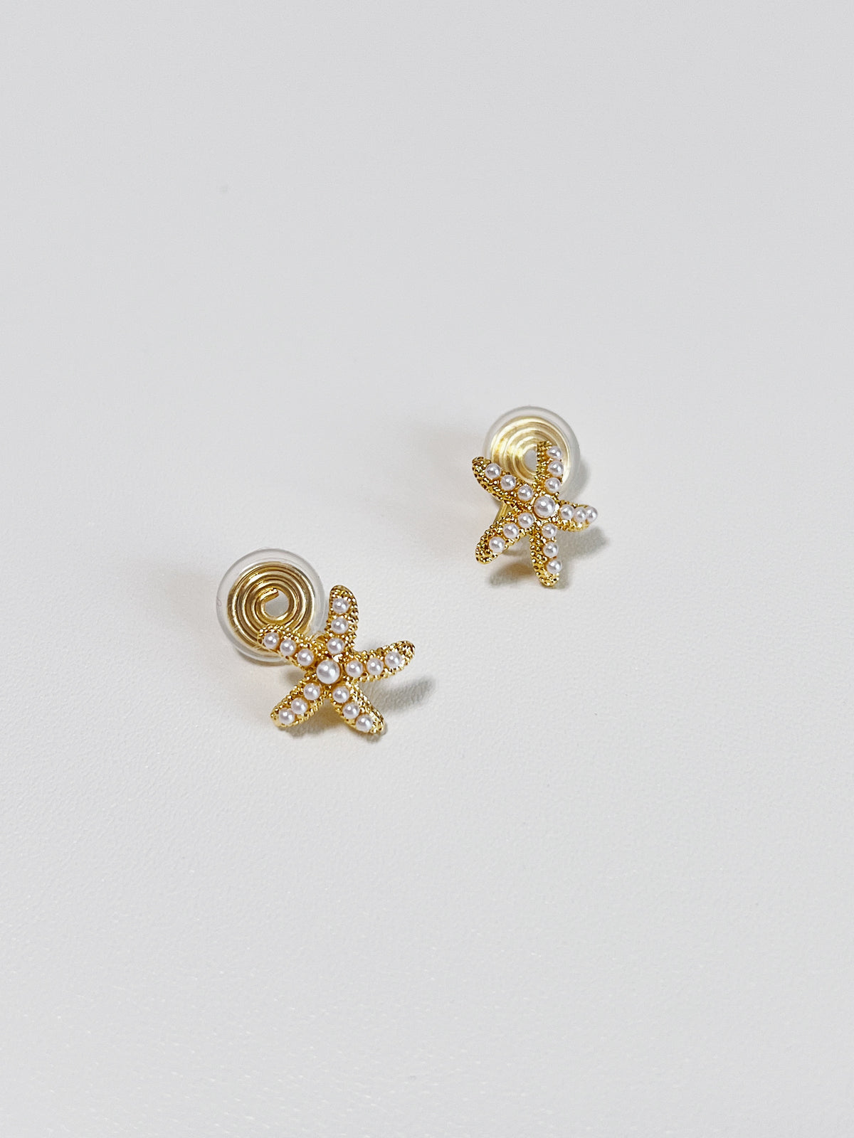 Technical view showing the gold-plated spiral spring coil clips and clear silicone comfort pads on the back of the non-pierced starfish earrings.