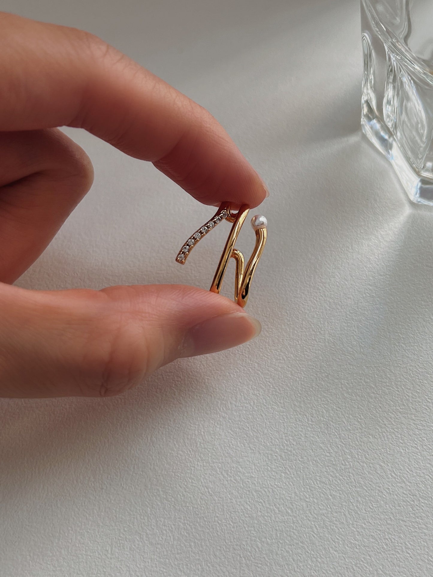 Fashionable gold ear cuff featuring a pearl and diamond accents, ideal for elegant outfits.