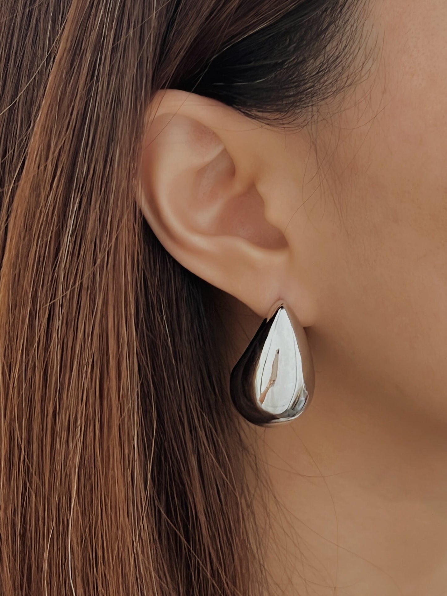 Silver drop earrings on woman's ear, luxury jewelry