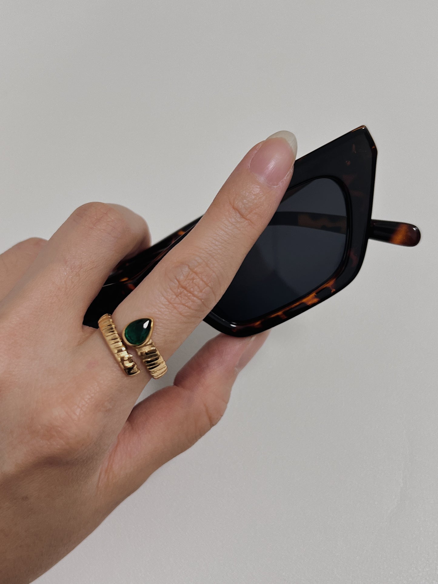 Gold ring with green teardrop stone, unique design, perfect for fashion-forward individuals.