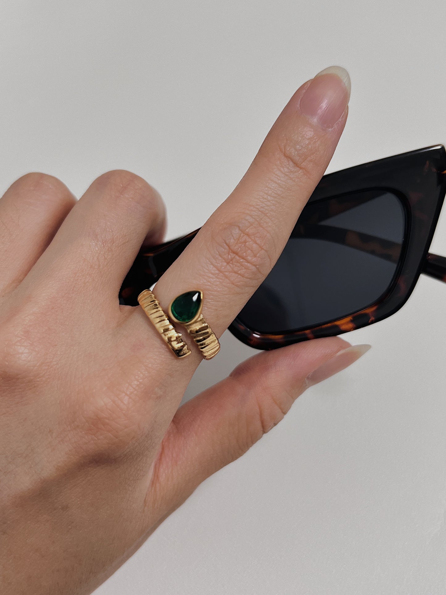 Unique gold ring featuring a green teardrop gemstone, perfect for luxury jewelry enthusiasts.