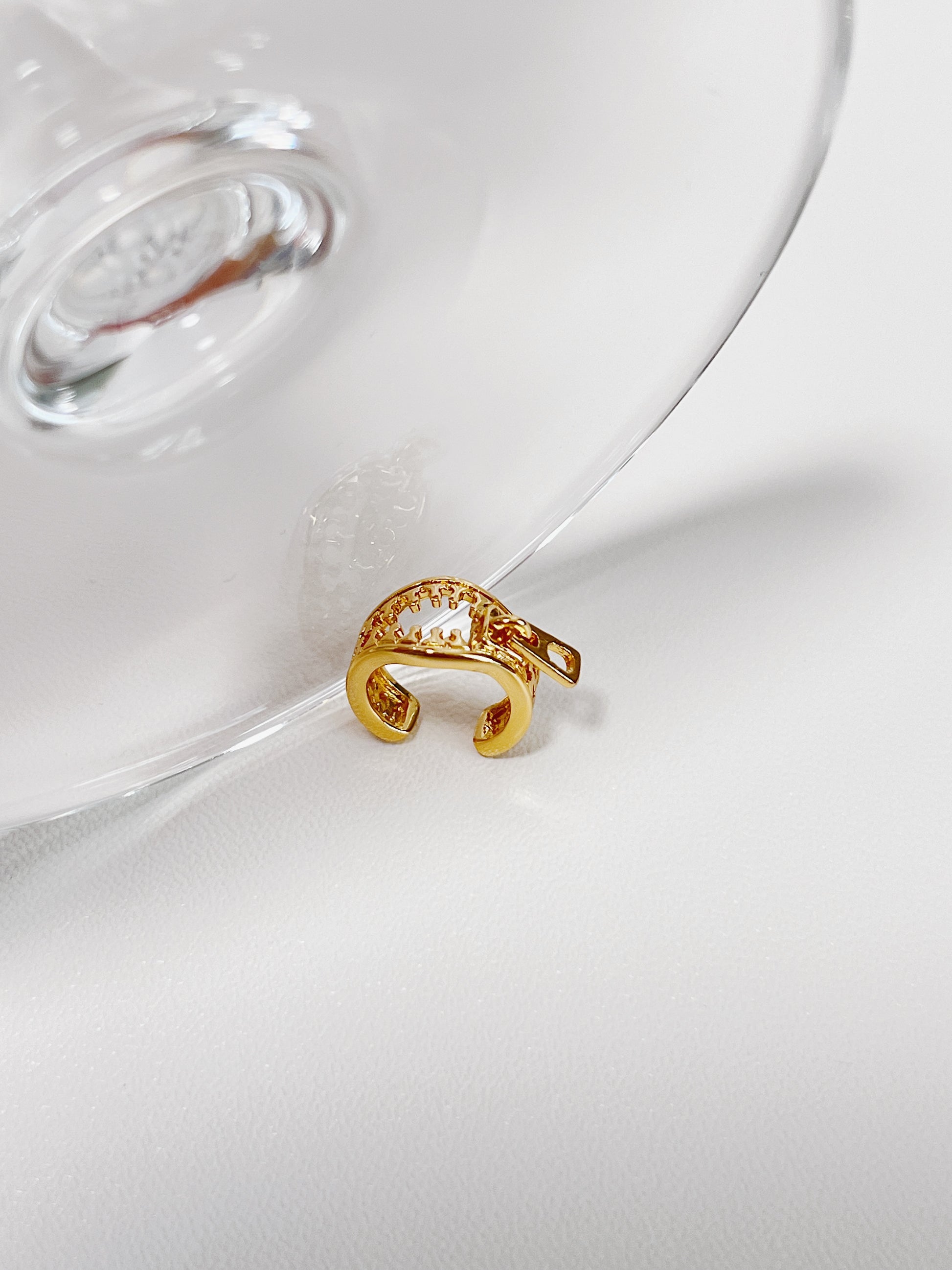 Gold ear cuff with a zipper design on a white surface
