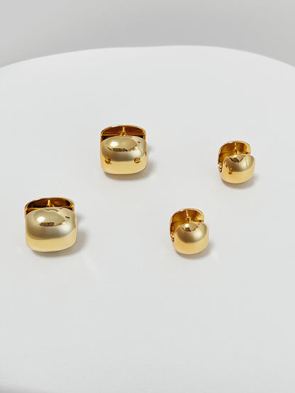 Set of 2 different sizes gold huggie hoop earrings on a white surface