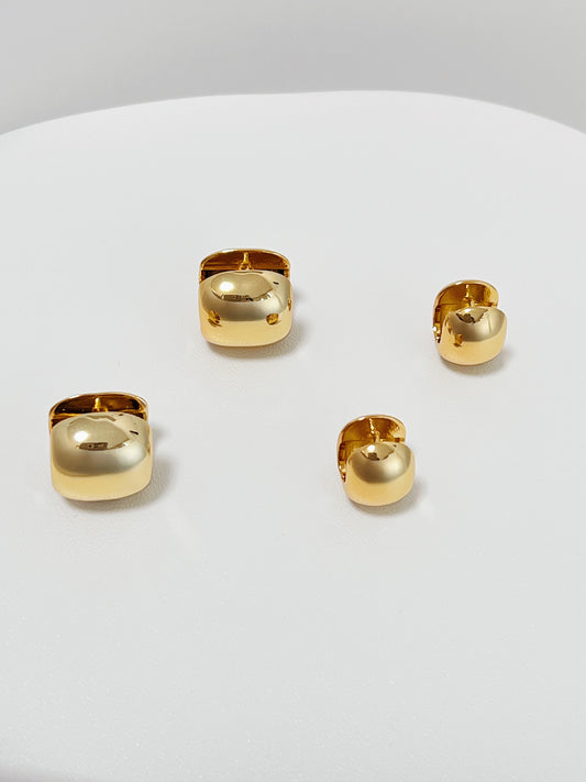 Set of 2 different sizes gold huggie hoop earrings on a white surface