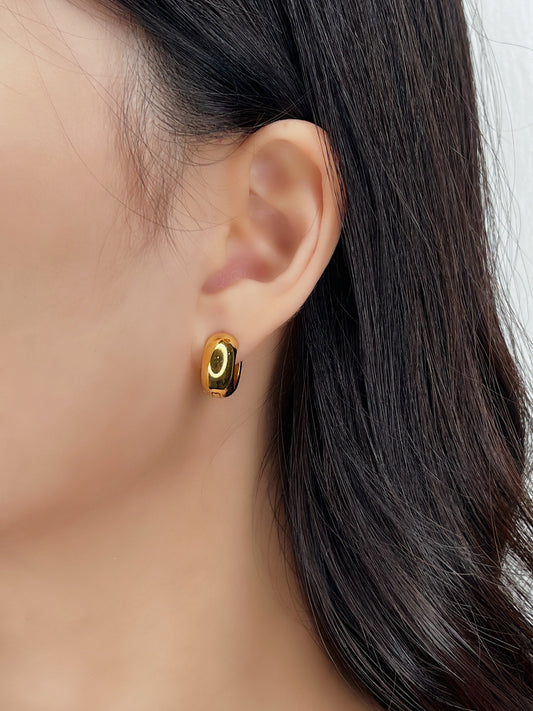Gold hoop earrings worn by a person with dark hair.