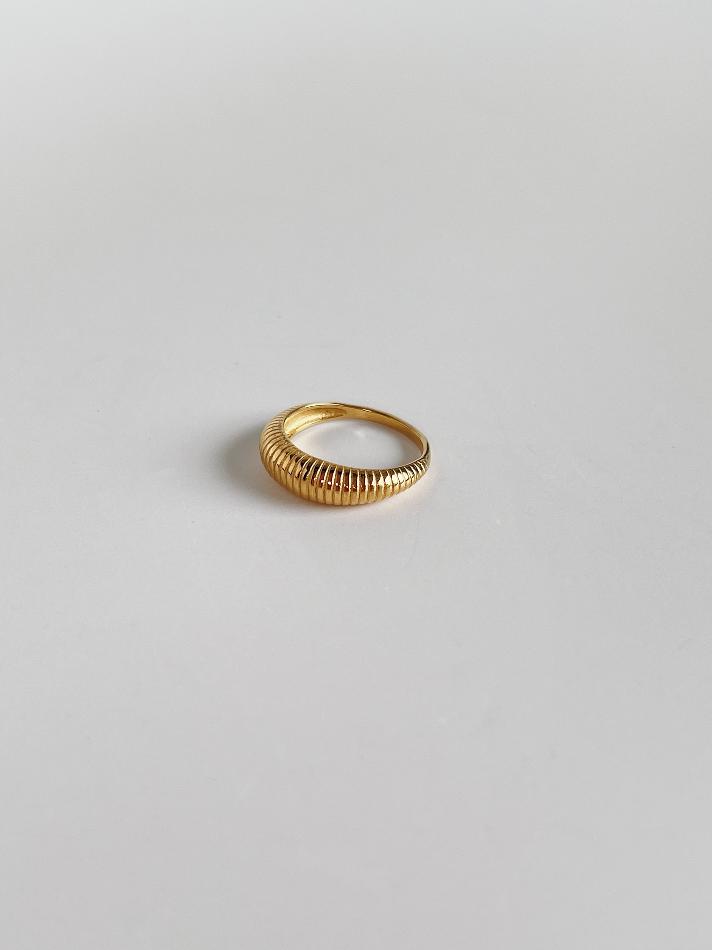 Gold vertical ribbed ring on a light gray background