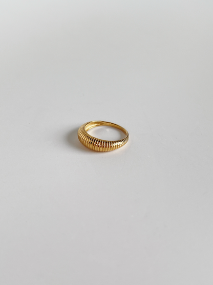 Gold vertical ribbed ring on a light gray background