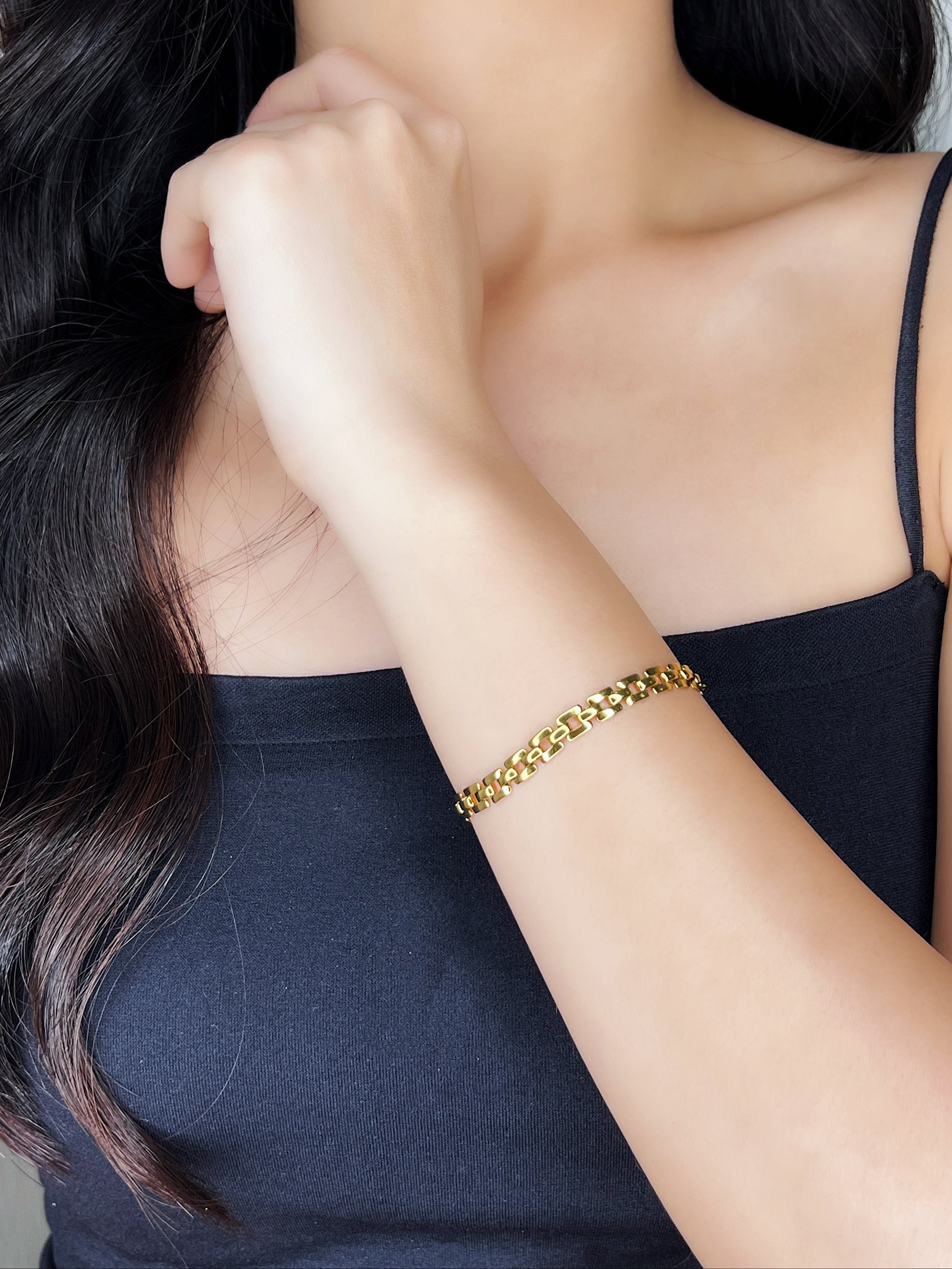 Woman wearing a gold bracelet with a plain background