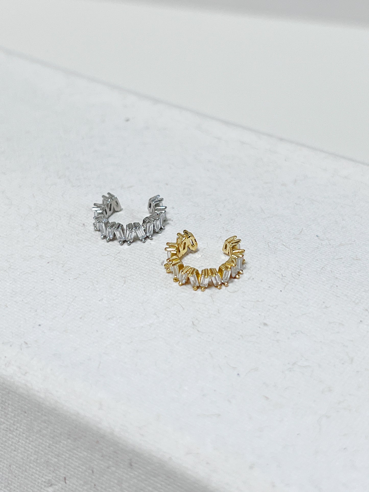 Gold and silver diamond cuff earrings on a light background