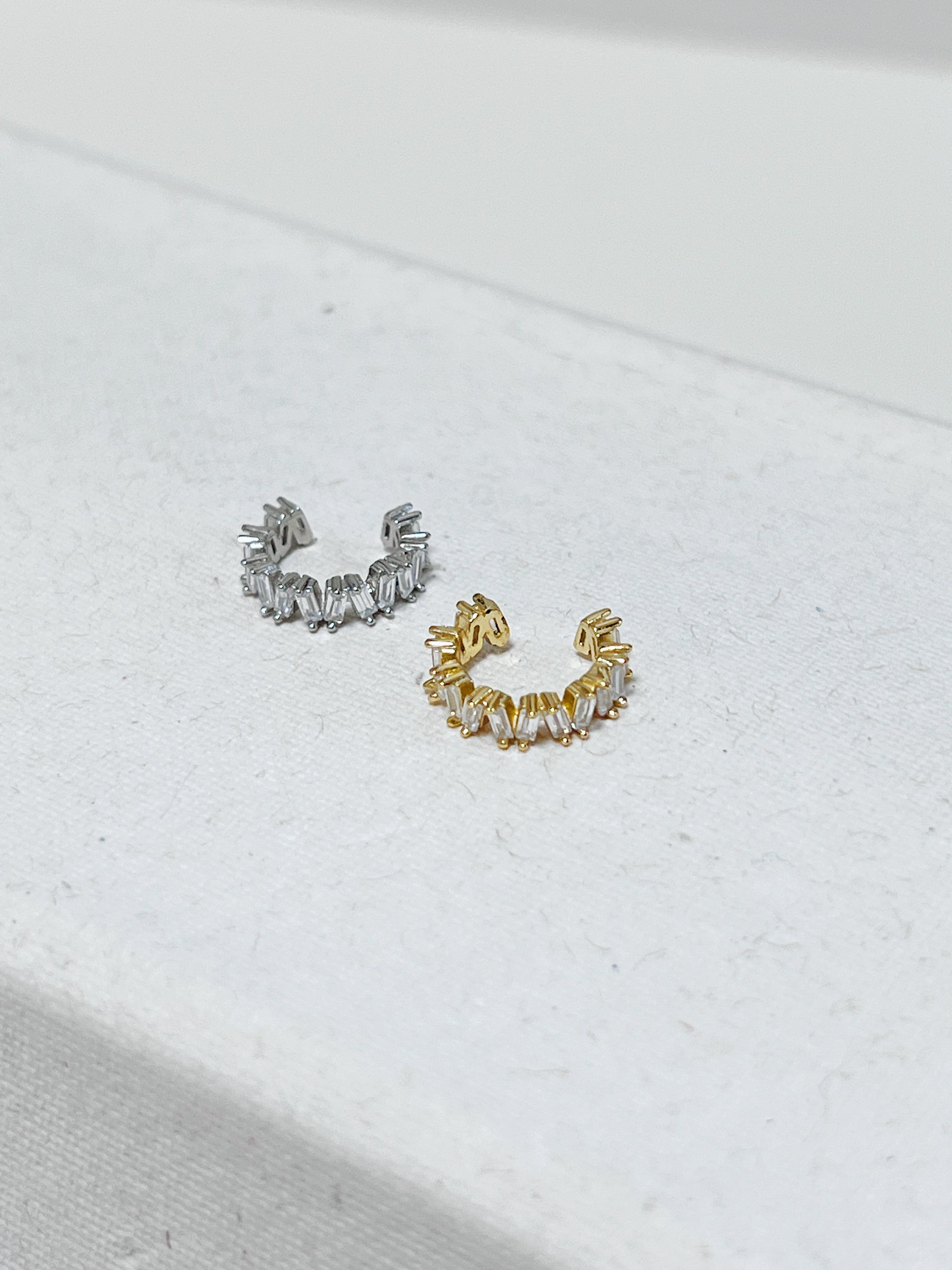 Gold and silver diamond cuff earrings on a light background