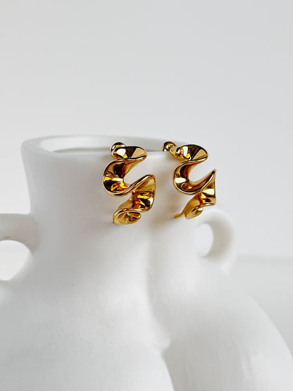 Gold spiral earrings on a white ceramic bust stand
