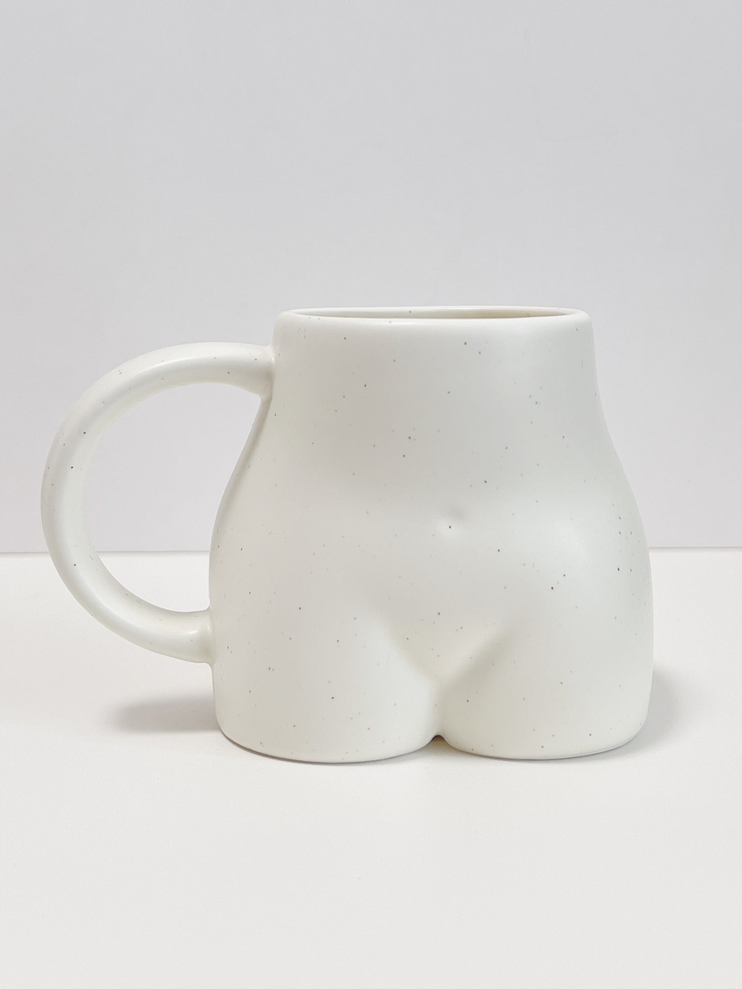 White ceramic mug shaped like a butt on a white background