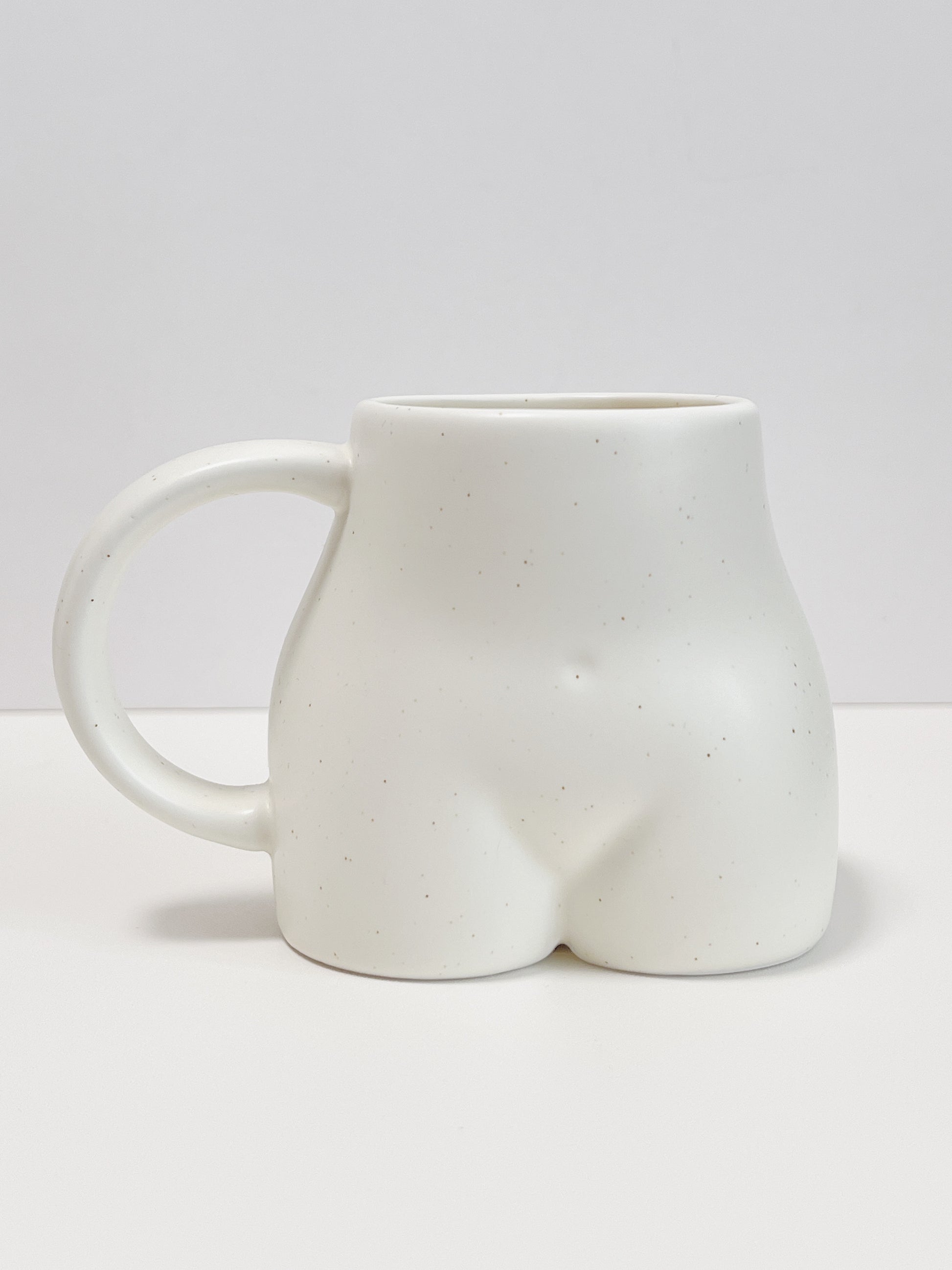 White ceramic mug shaped like a butt on a white background