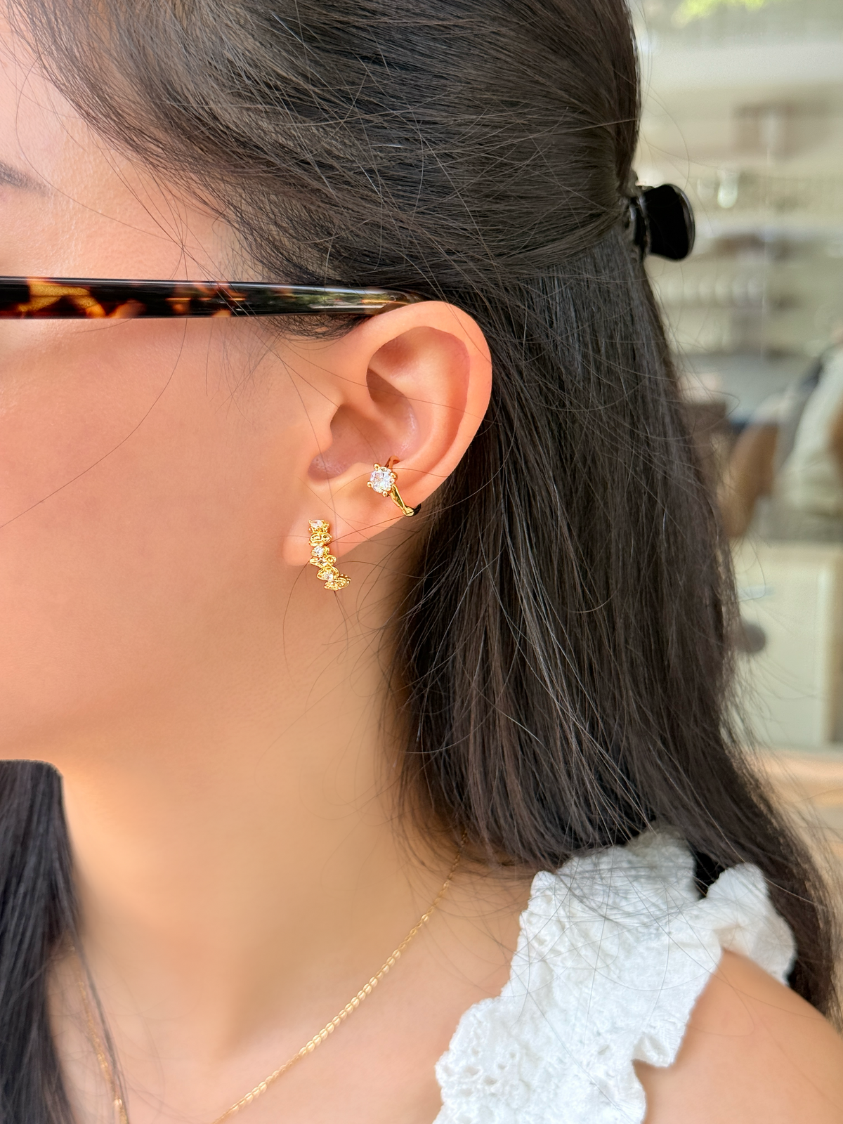 Side angle lifestyle image of an 18k gold plated celestial ear climber clip-on earring catching light during a golden hour shoot