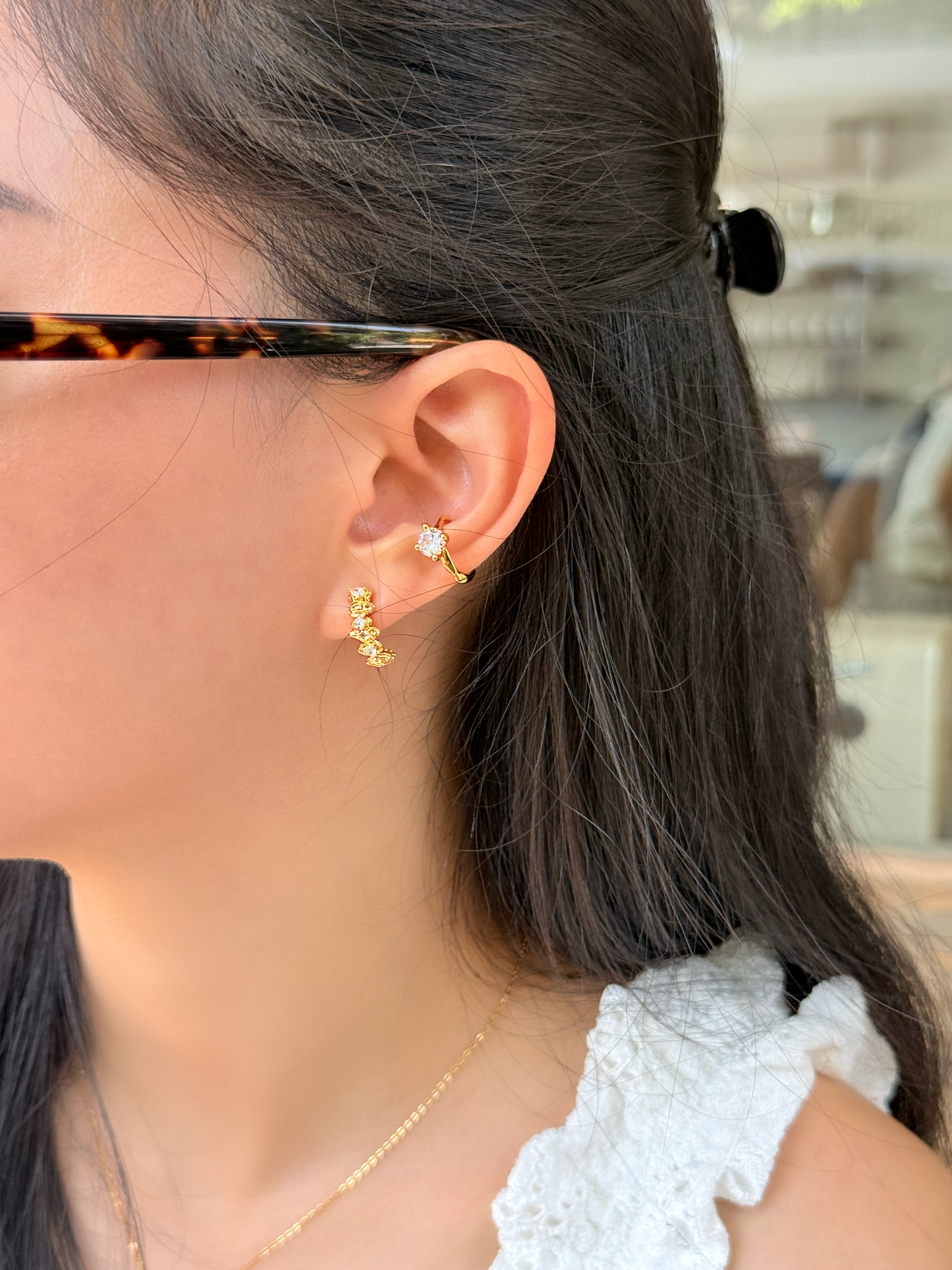 Side angle lifestyle image of an 18k gold PVD celestial ear climber clip-on earring catching light during a golden hour shoot