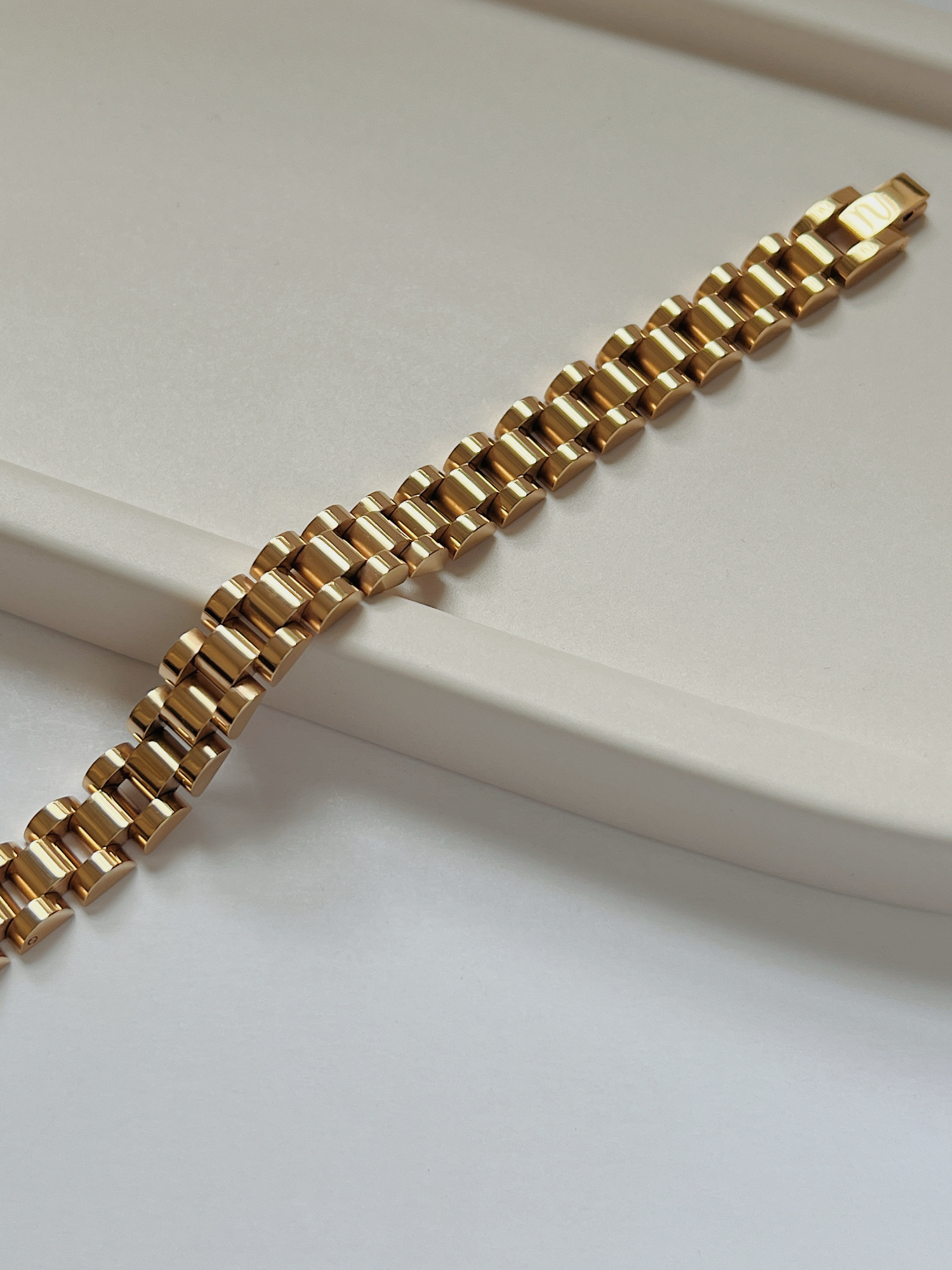 Close-up detail of the secure flush-folding clasp on the 18K gold PVD watch link bracelet.
