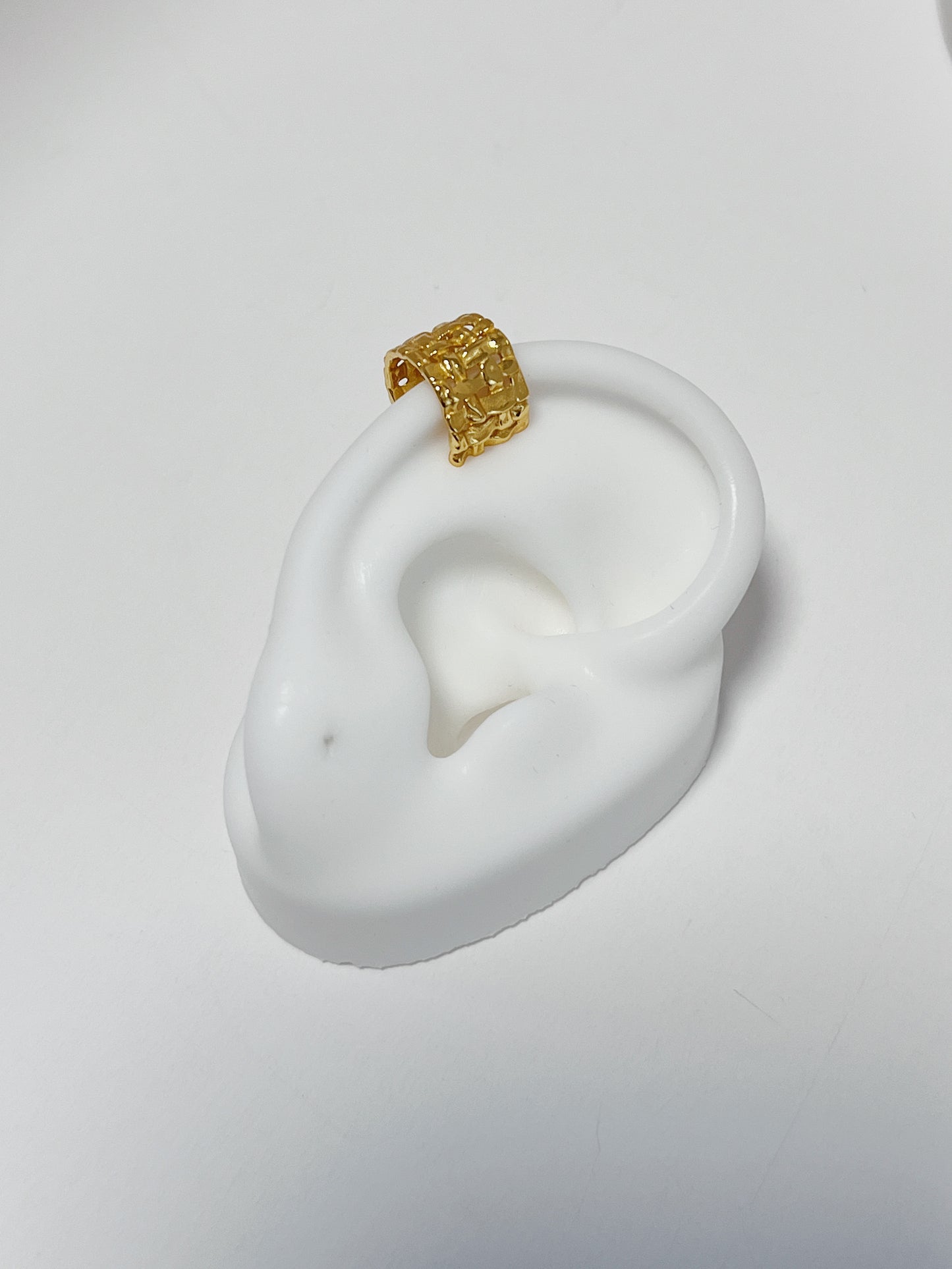 Close-up of white silicone ear featuring the 18k gold vermeil woven cuff.