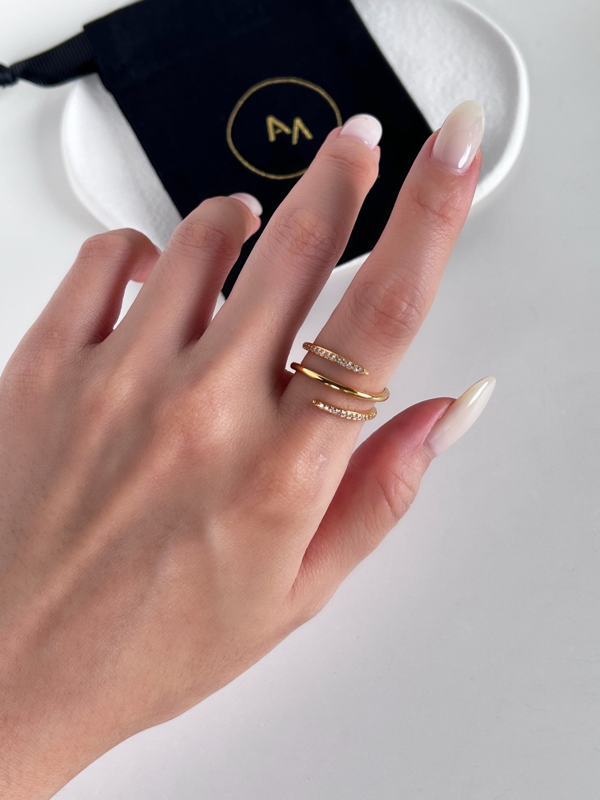 Hand wearing gold rings embedded with diamonds with a blurred background