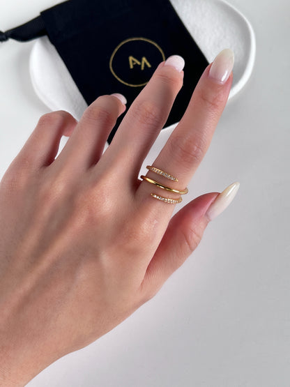 Hand wearing gold rings embedded with diamonds with a blurred background