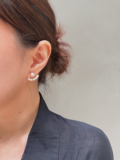 Close-up of an ear wearing a pearl ear jacket earring with a neutral background