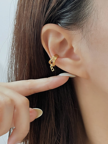Gold cuff earring being worn and pointed to by a hand