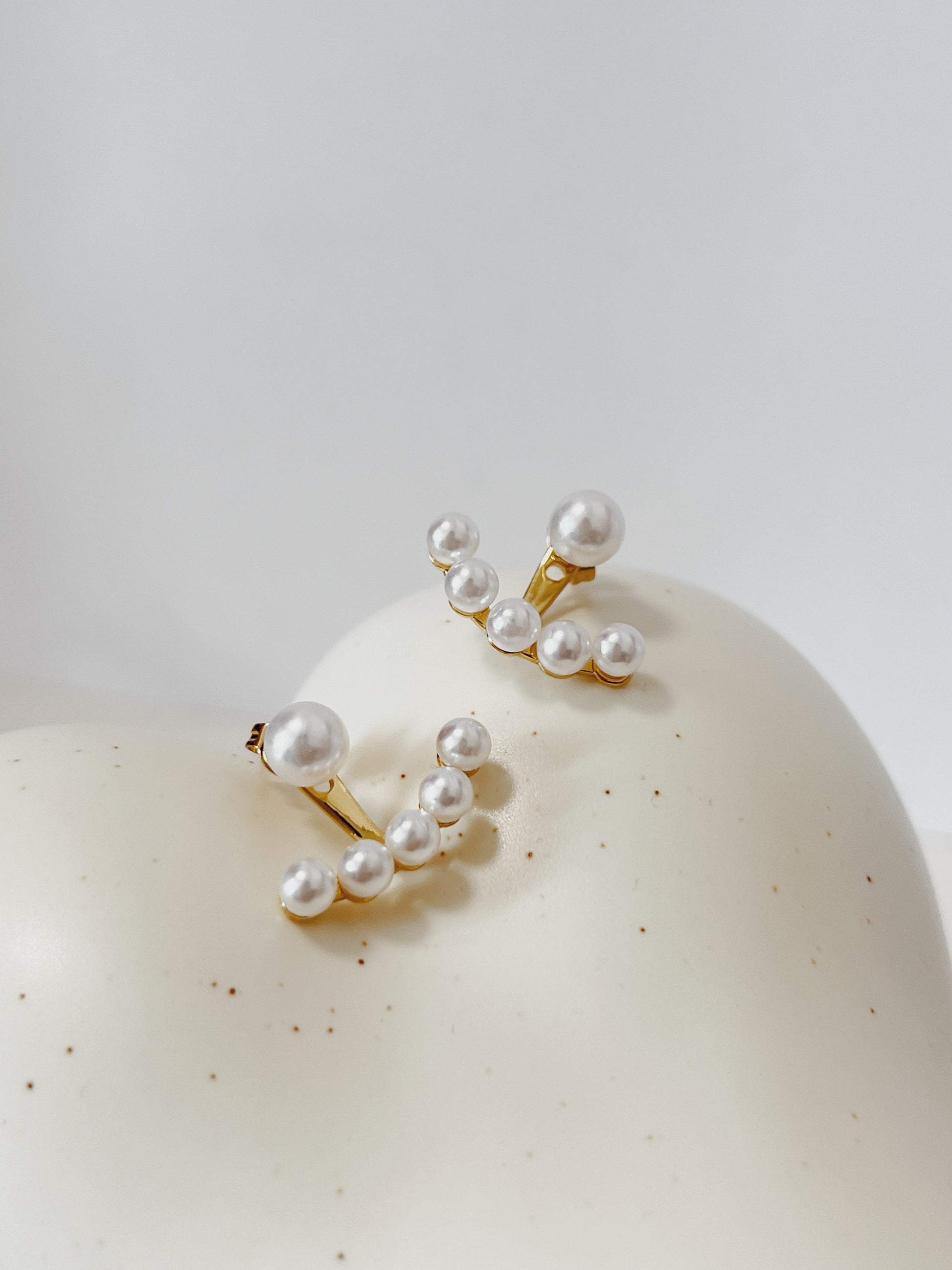 Pearl earrings on a white surface with a light gray background