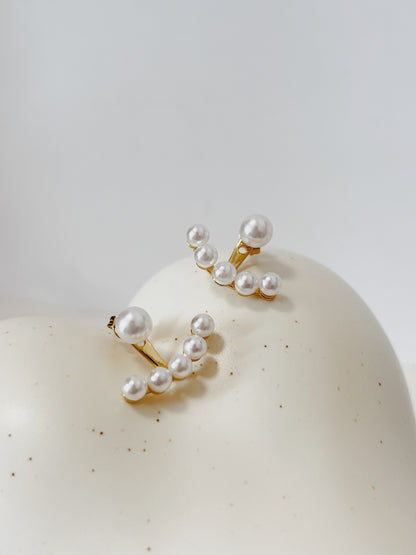 Pearl earrings on a white surface with a light gray background