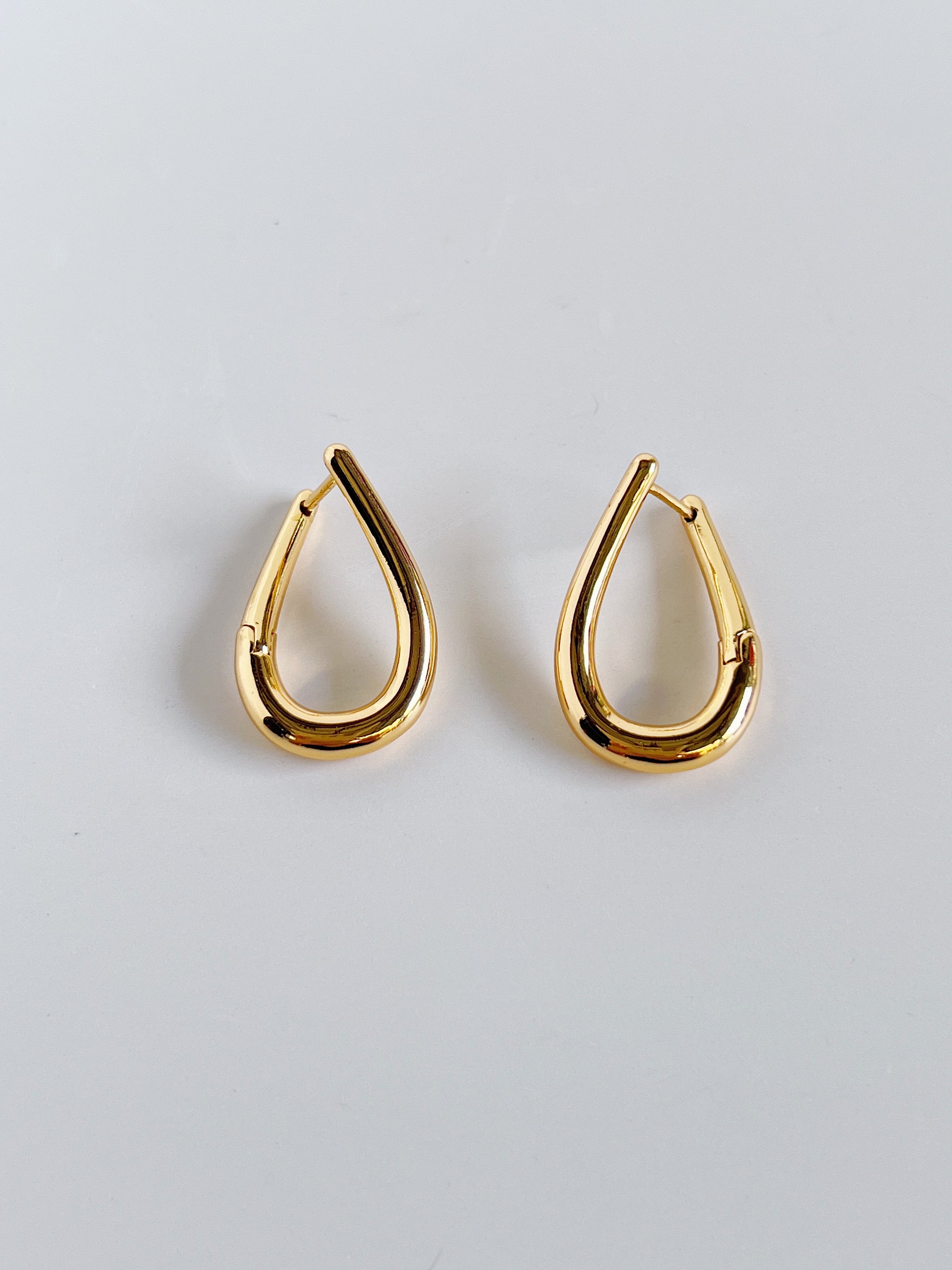 Gold minimal hoop earrings on a light gray background