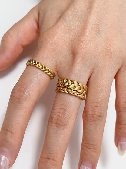 Gold braided ring on a finger against a white background