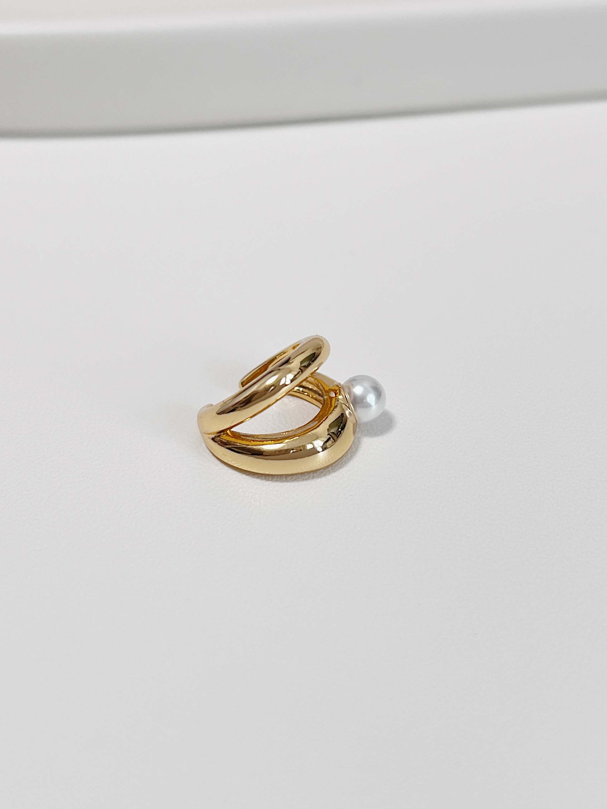 Gold ear cuff with a pearl on a white background