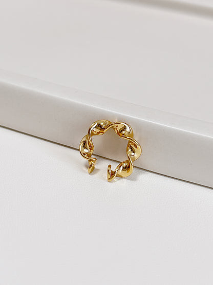 Gold twisted ear cuff on a white surface