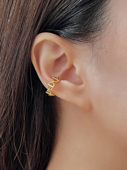 Close-up of an ear wearing a gold chain link ear cuff