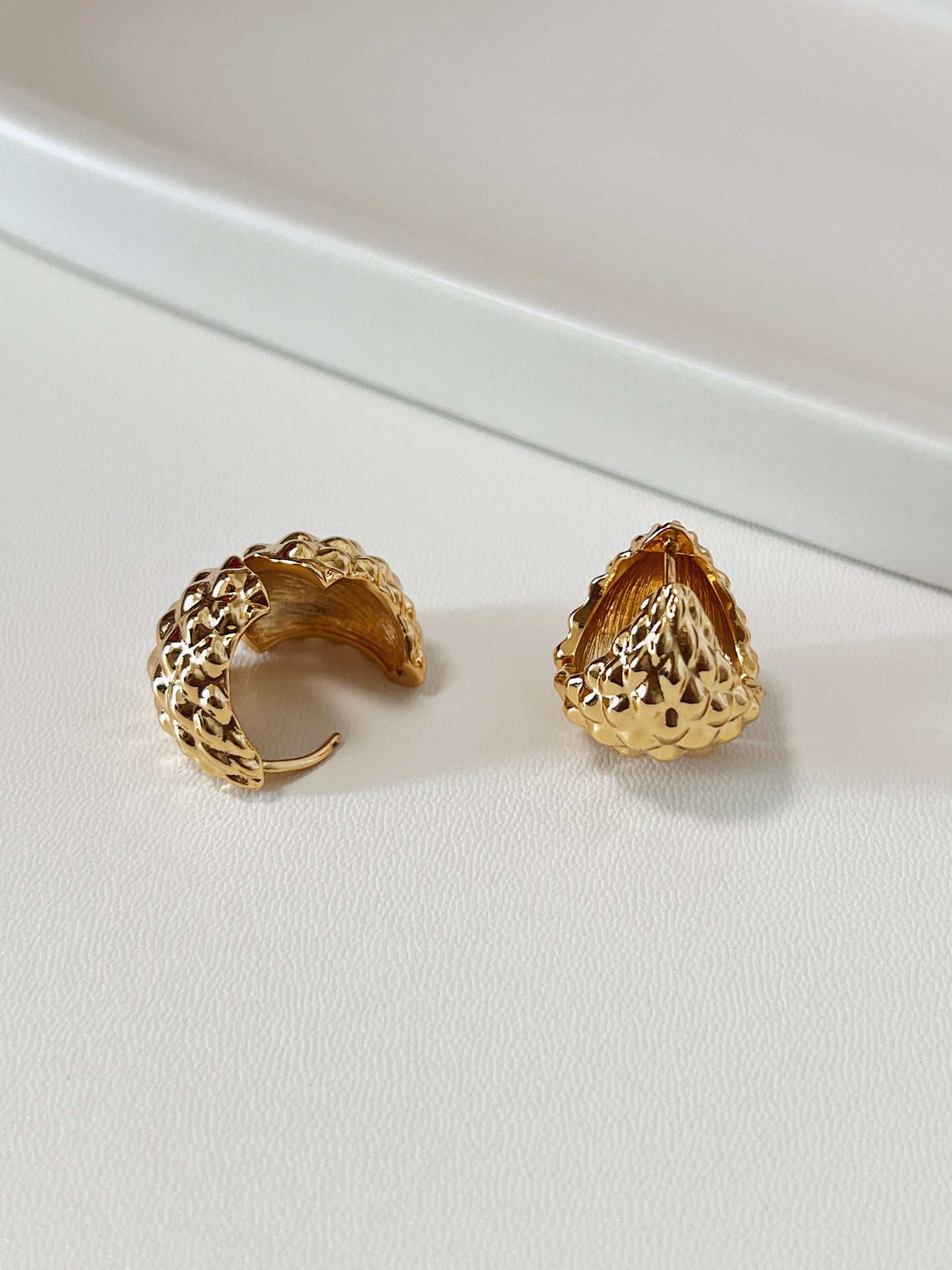 Gold spiky hoop earrings on a white surface