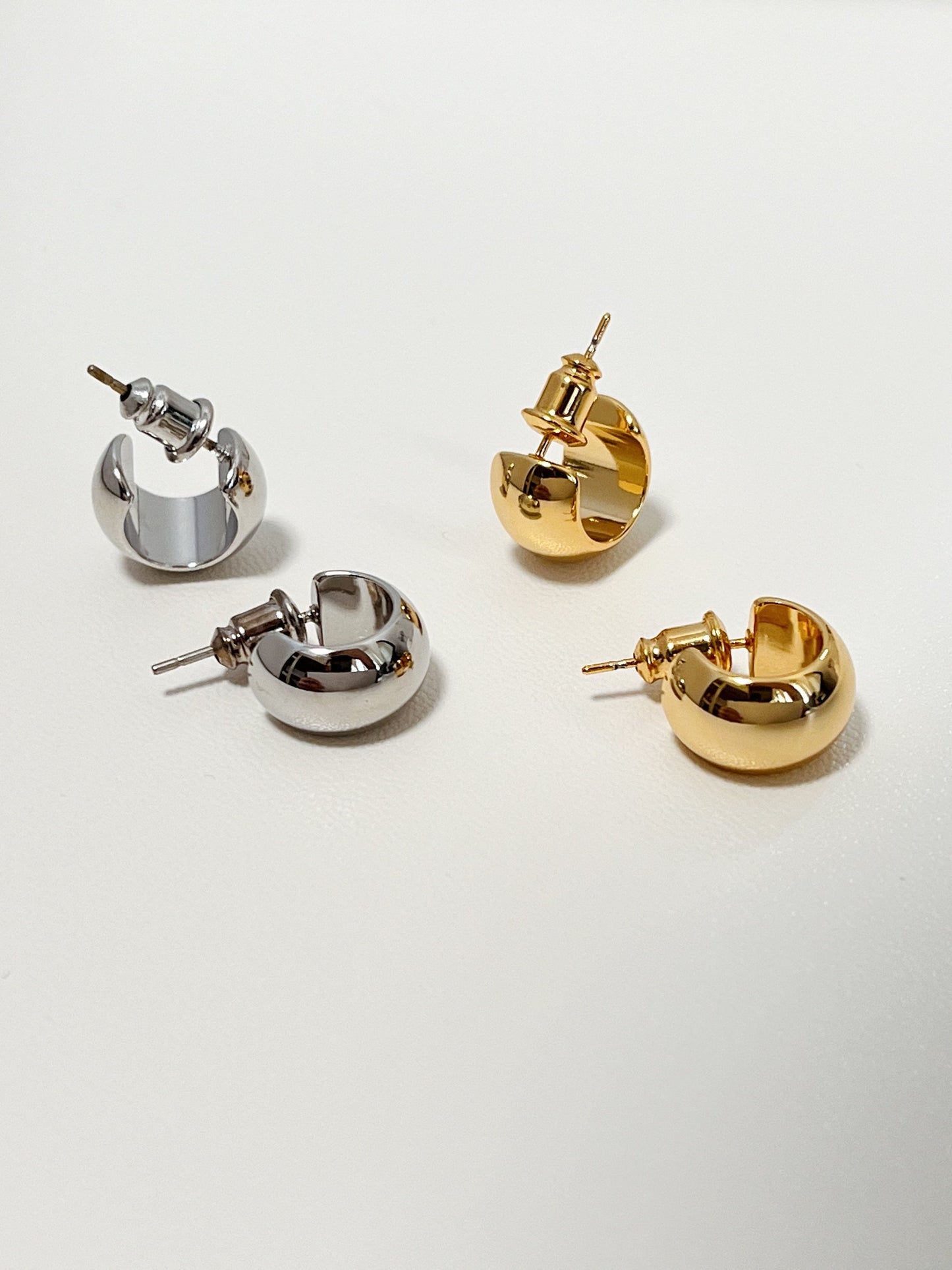 Trendy gold and silver-colored huggie hoop earrings with a classic, minimalist design.