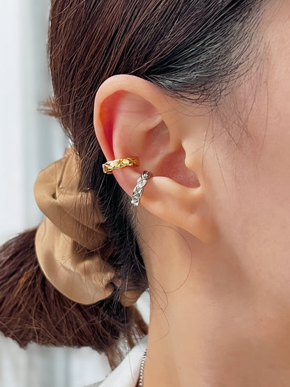 Close-up of an ear wearing a gold and silver diamond ear cuff earring with a blurred background