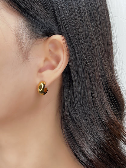 Close-up of a person wearing a gold hoop earring with a blurred background
