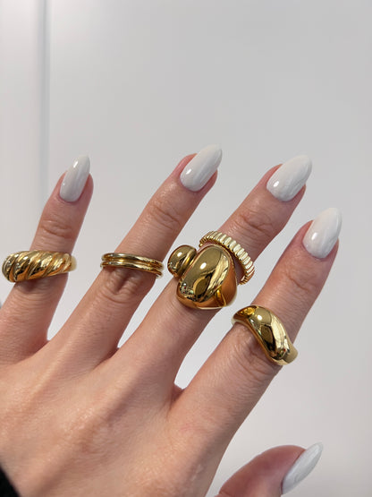 Hand wearing multiple gold rings with a plain background