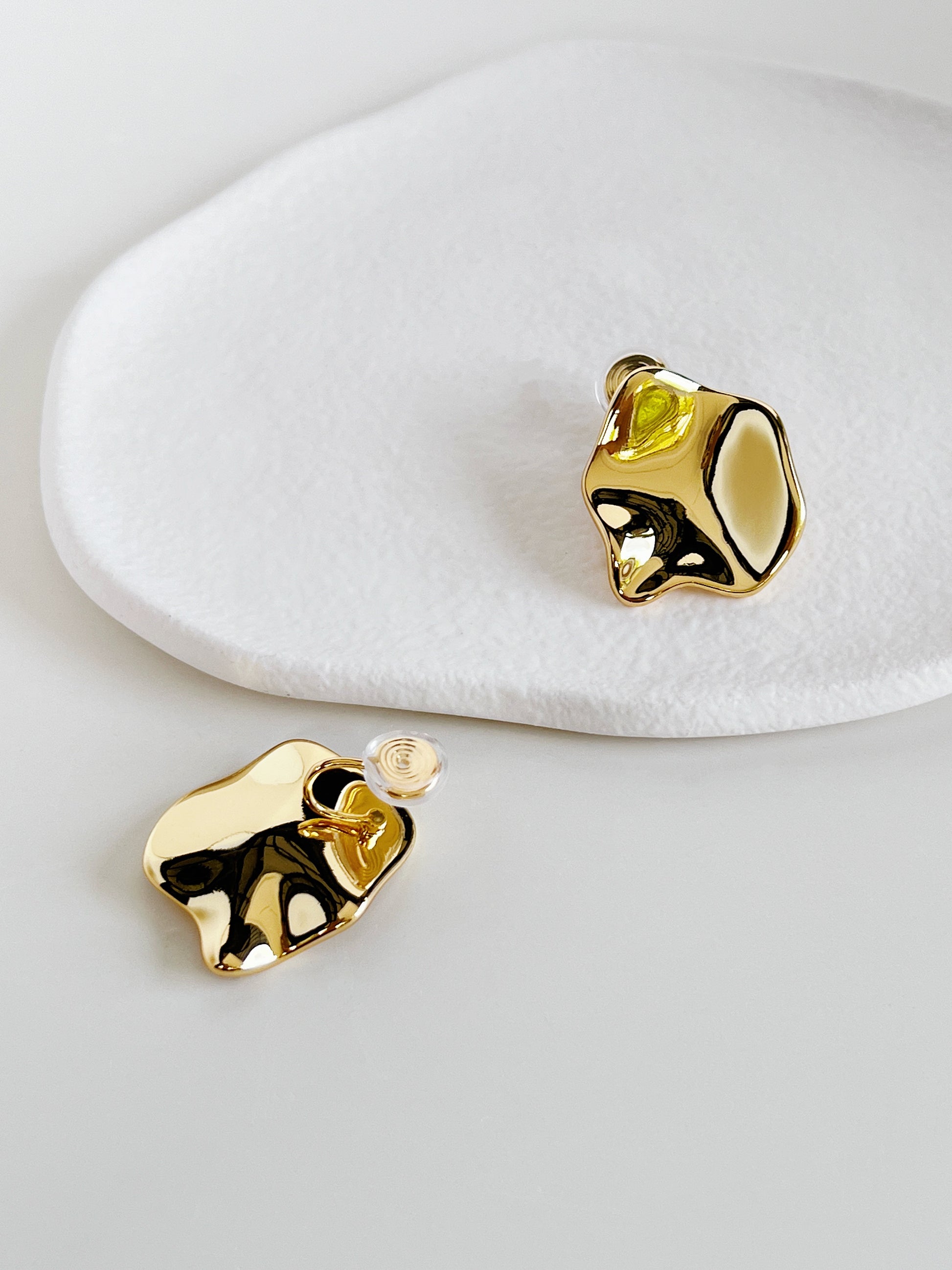Gold clip on earrings on a white surface