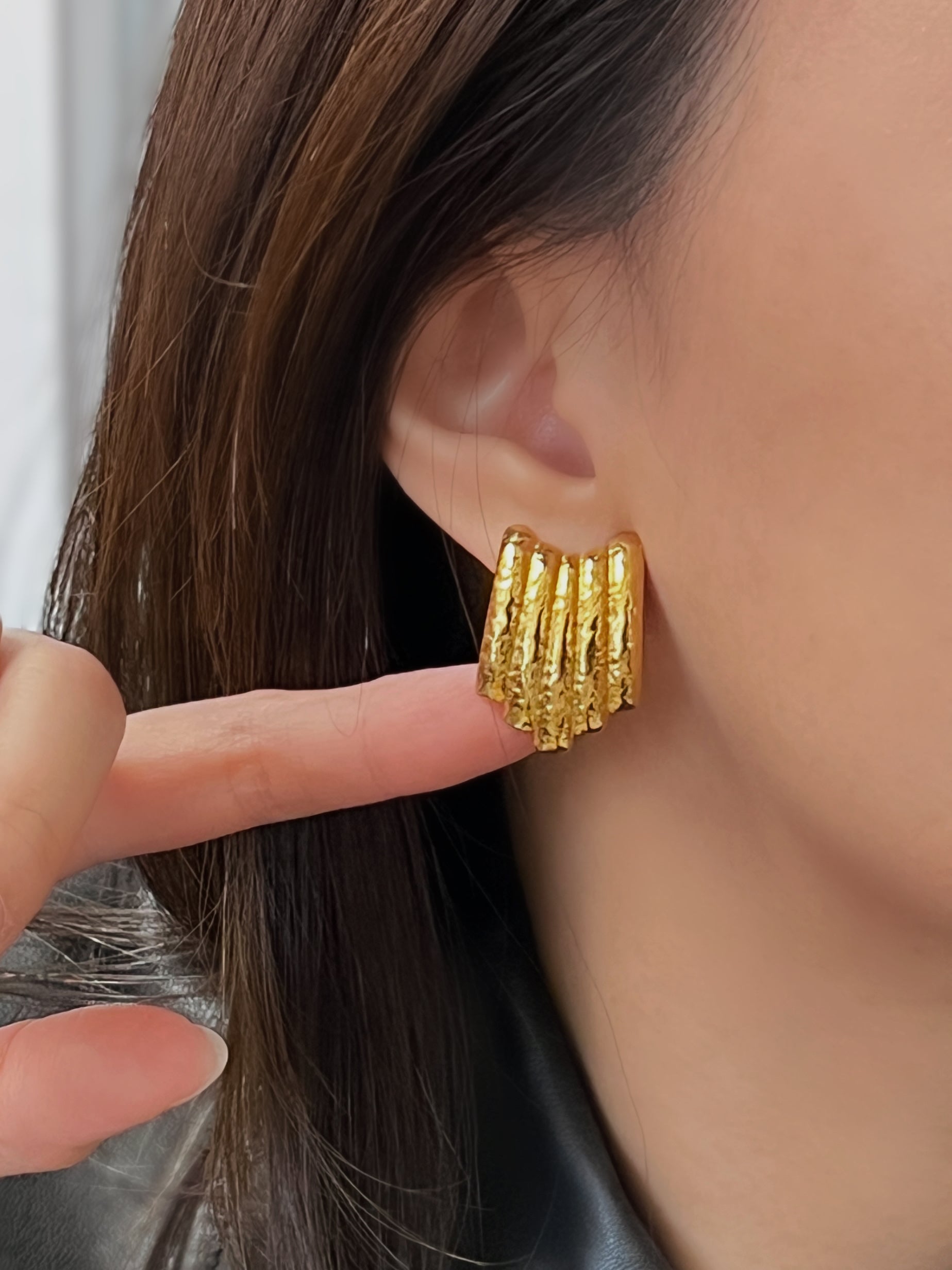 Gold ribbed stud earrings with a distinctive hammered texture.