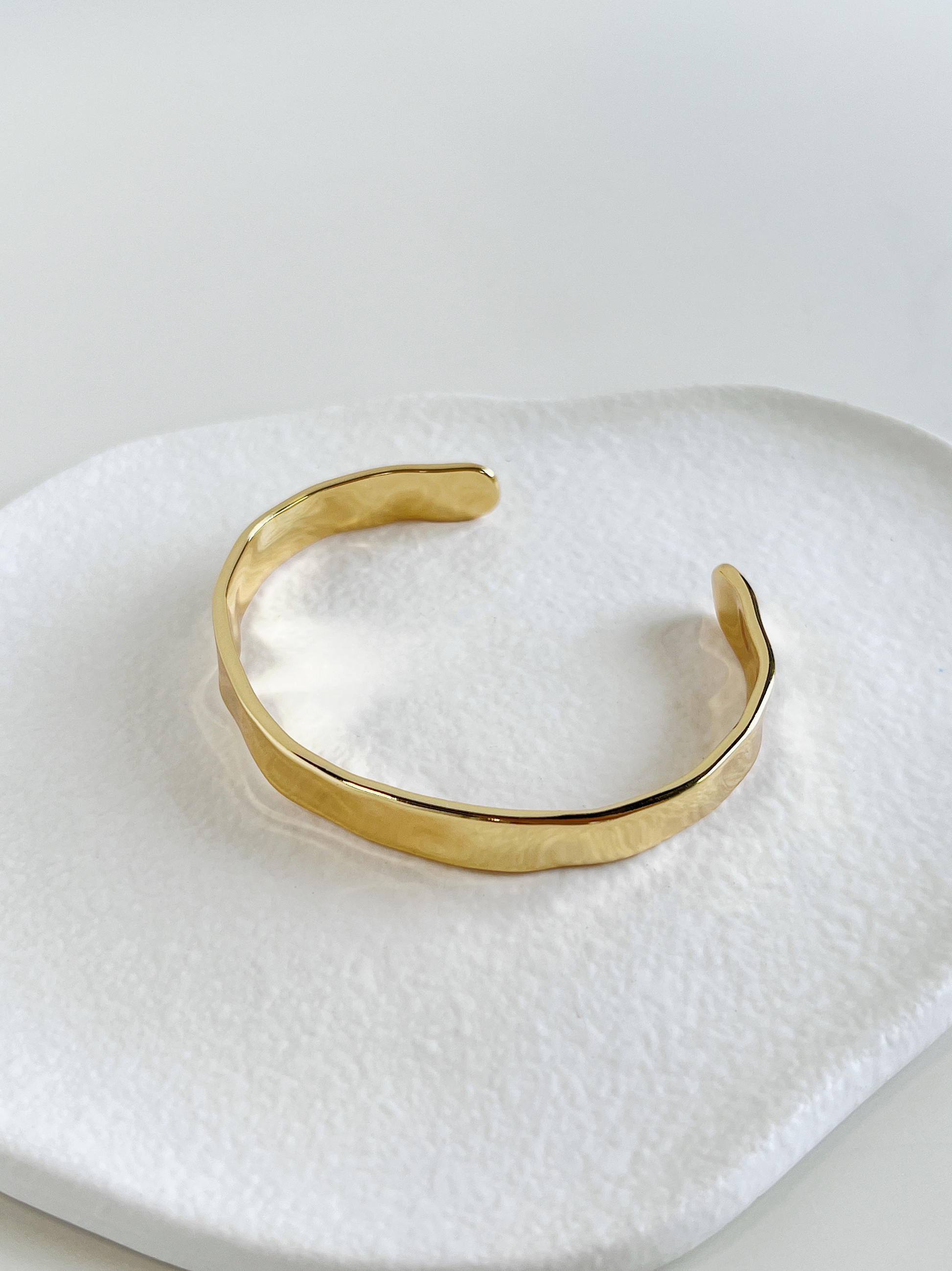 Refined gold-colored hammered open cuff bracelet, a sophisticated and stylish accessory.