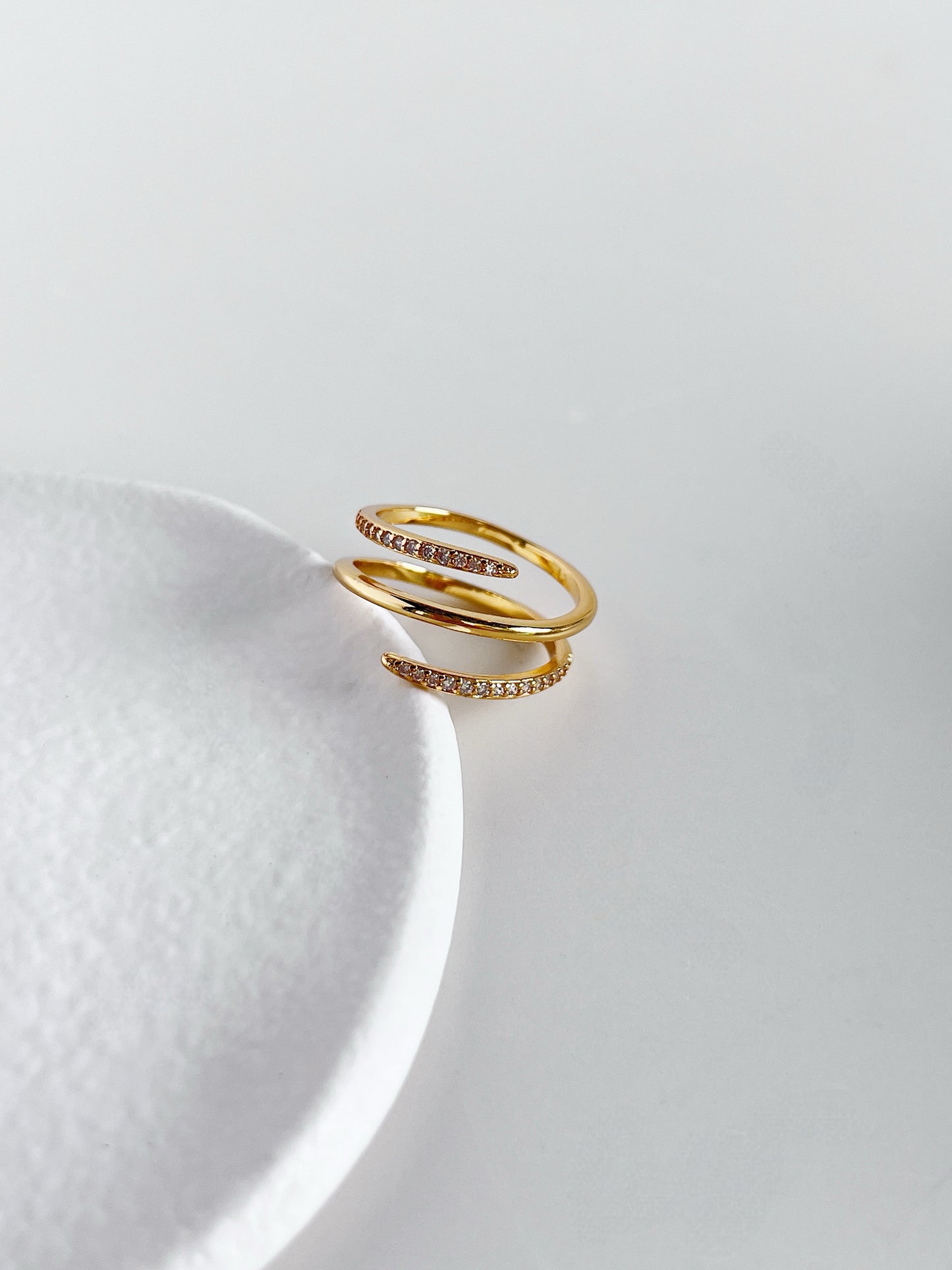 Gold ring with small diamonds on a white ceramic plate