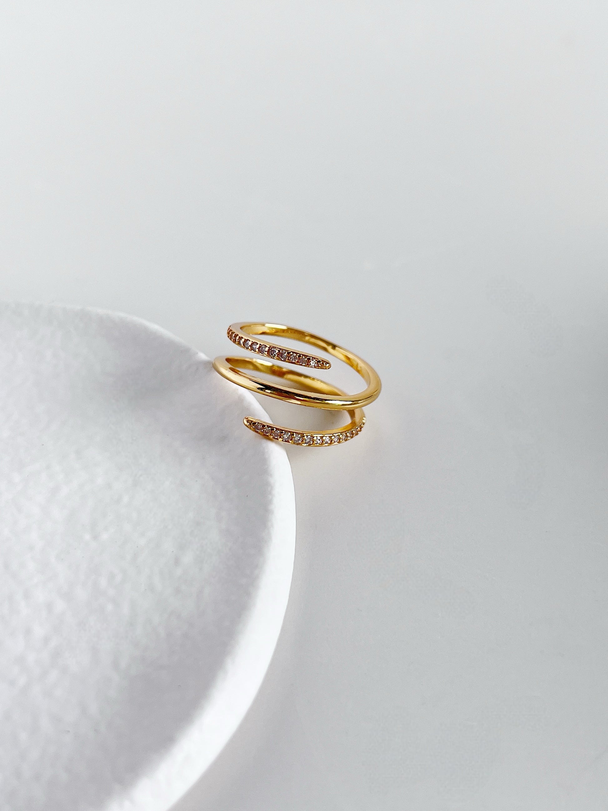 Gold ring with small diamonds on a white ceramic plate