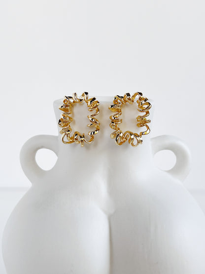 Gold curly earrings on a white bust