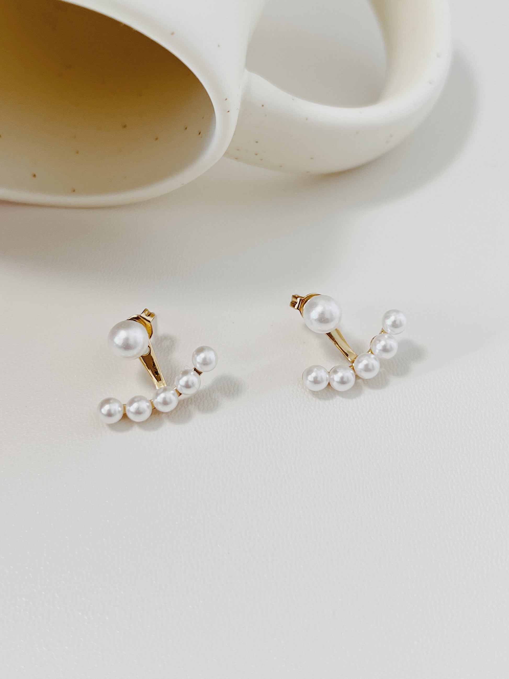 Pair of pearl ear jacket earrings on a light background